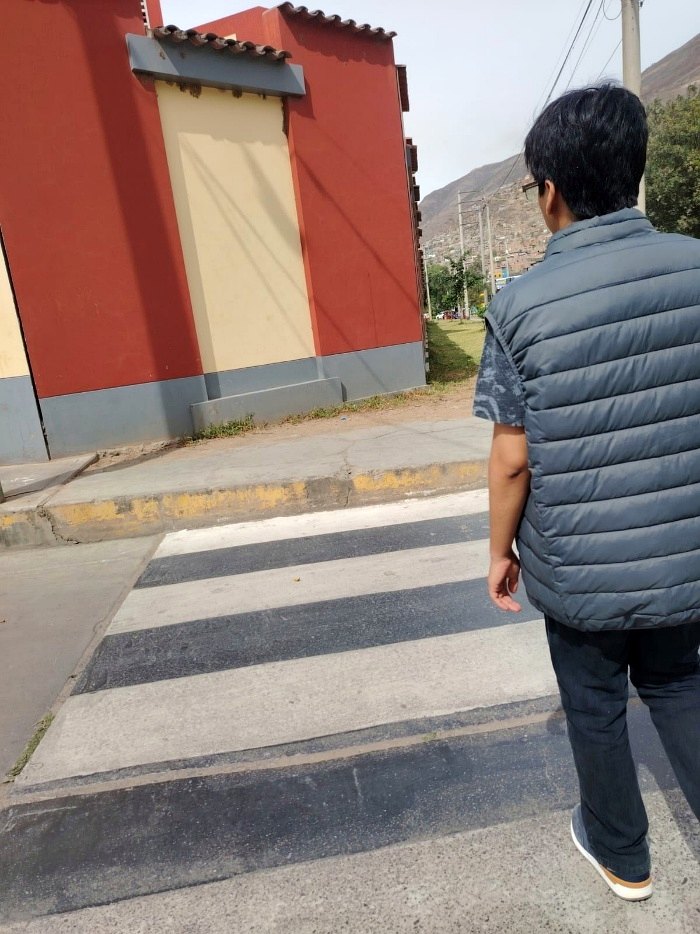 Persona con el prototipo puesto cruzando un paso peatonal, con los recuadros de la simulación